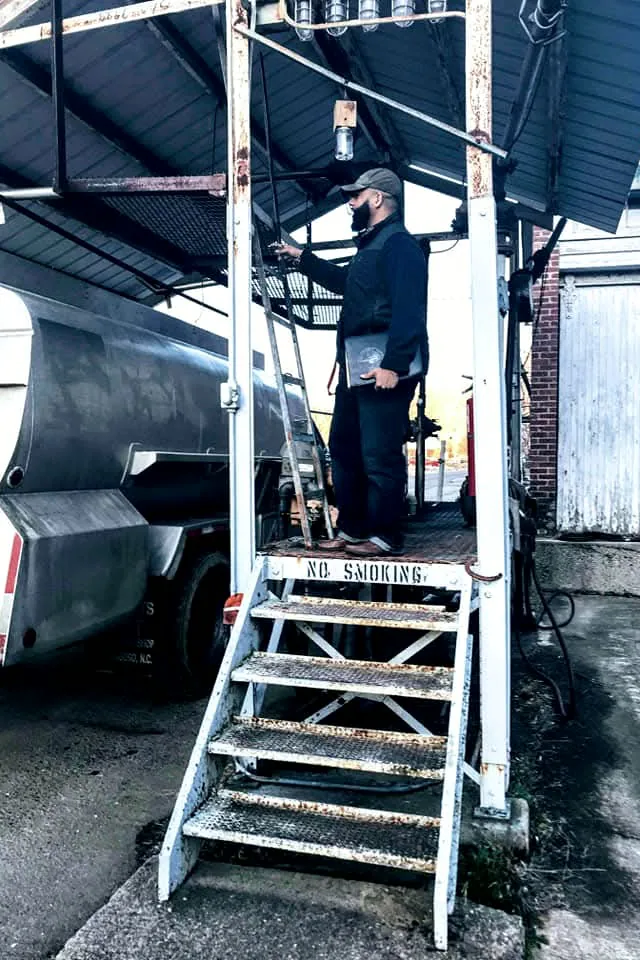 Representative on the platform of a truck loading rack beside a fuel tanker