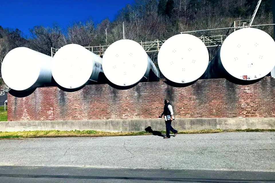 A B. Simmons representative walks a row of horizontal storage tanks mounted on a brick wall